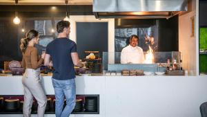 un hombre y una mujer preparando comida en una cocina en voco Brisbane City Centre, an IHG Hotel en Brisbane