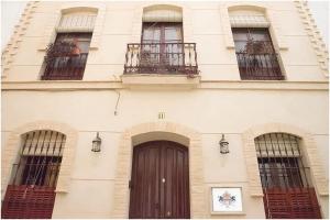 een gebouw met een bruine deur en drie ramen bij Casa de la Judería Doña Pilar in Sevilla