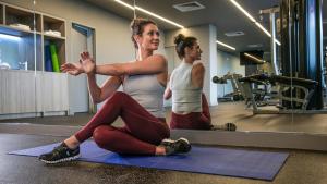 a woman sitting on a yoga mat in front of a mirror at voco Brisbane City Centre, an IHG Hotel in Brisbane