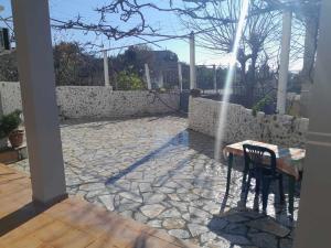 un patio con mesa, sillas y pared de piedra. en Kalemi Sunrise Studios en Borsh