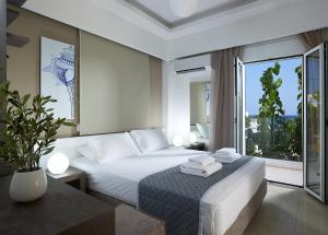 イエラペトラにあるCoral Apartmentsのベッドと大きな窓が備わるホテルルームです。
