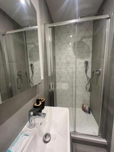 uma casa de banho com um lavatório e um chuveiro em London Heathrow Airport Apartment Voyager House Terminal 12345 - EV Electric and Parking available! em New Bedfont