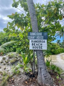 um sinal numa árvore em frente a uma casa de praia em Rangiroa Beach House em Avatoru