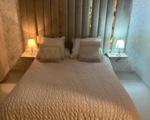 a large bed with pillows and two lamps on tables at Appartement Plage près d’Agadir in Aourir