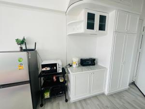 uma cozinha com um frigorífico e um micro-ondas em The most prosperous seaside seaview apartment in Jomtien(Tub, high speed Wi-Fi, Projector) em Praia de Jomtien