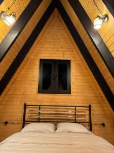 a bed in a room with a wooden wall at Vintage Cabin in Kutaisi