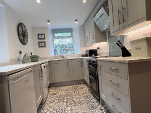 cocina con armarios blancos y suelo de baldosa en Holly Cottage, en Bowness-on-Windermere