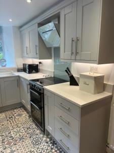 uma cozinha com armários brancos e um forno com placa de fogão em Holly Cottage em Bowness-on-Windermere