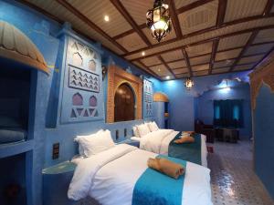 una camera con due letti in una camera blu di Kasbah Yasmina Hotel a Lac Yasmins