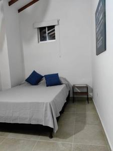 a bedroom with a bed with blue pillows and a window at Aparta-estudio completo en Itagüí - 501 in Itagüí
