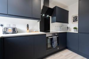 a kitchen with black cabinets and white counter tops at Raincliffe Nook by NordStay in Knowsthorpe