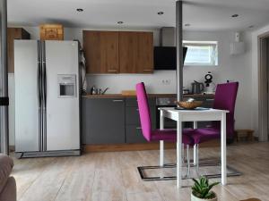 a kitchen with a refrigerator and a table and purple chairs at Mandelas Cozy Lounge in Schmelz
