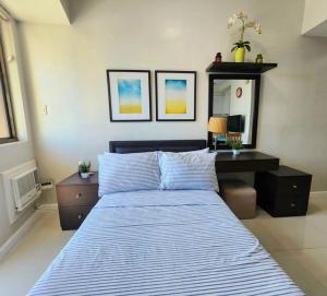 een slaapkamer met een bed en een bureau met een blauw gestreept dekbed bij KL Residences Cosy Studio with Gym, Pool and Sauna near Greenbelt and Park in Manilla