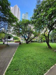 een park met bomen en groen gras en gebouwen bij KL Residences Cosy Studio with Gym, Pool and Sauna near Greenbelt and Park in Manilla