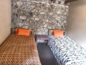 two beds in a room with a stone wall at HOSTEL SAMANA WASI CHAULLAY in Cusco