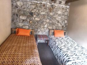 two beds in a room with a stone wall at HOSTEL SAMANA WASI CHAULLAY in Colcapampa +31 photos