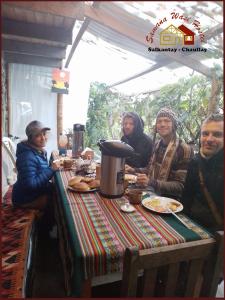 a group of people sitting at a table with food at HOSTEL SAMANA WASI CHAULLAY in Cusco