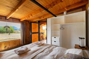 a bedroom with a bed and a large window at Piuke Mapu Patagonia Hostel in Cholila