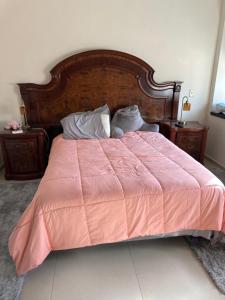 łóżko z pomarańczowym kocem i 2 poduszkami w obiekcie Av de las rosas w mieście Guadalajara