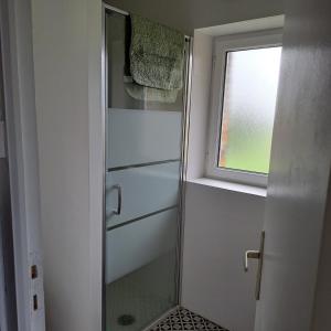 a shower with a glass door and a window at Maison de charme en campagne, 5 min du haras du pin in Nonant-le-Pin