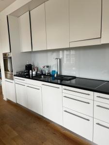 uma cozinha com armários brancos e bancadas pretas em Casa Bolero em Horgen
