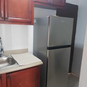 a kitchen with a stainless steel refrigerator and wooden cabinets at Ocean Breeze Apartment in La Romana in La Romana