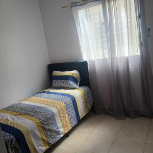 1 dormitorio con 1 cama con edredón y ventana en Ocean Breeze Apartment in La Romana, en La Romana
