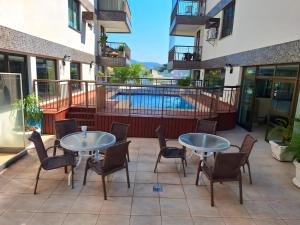 un patio con mesas y sillas y una piscina en Camboinhas Inn en Niterói