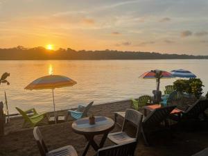 a beach with chairs and tables and umbrellas on the water at Hotel Sunset Rooms in Tortuguero