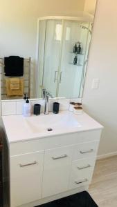 a white bathroom with a sink and a mirror at Maymorn Orchard Suite in Upper Hutt