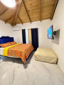 a bedroom with a bed and a ottoman in it at Richie’s House En Licey Al Medio in Santiago de los Caballeros