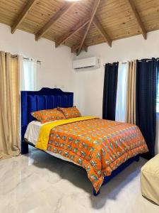 a bedroom with a bed with an orange blanket at Richie’s House En Licey Al Medio in Santiago de los Caballeros