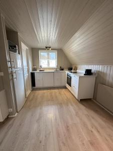 a large kitchen with white cabinets and a large window at Cabin in Lava Village with hot tub in Selfoss