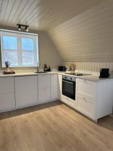 cocina grande con armarios blancos y ventana en Cabin in Lava Village with hot tub, en Selfoss