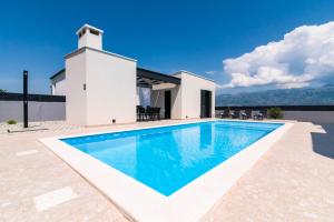 une piscine en face d'une maison avec un phare dans l'établissement Designer Villa Neva With Magic Velebit View, à Ražanac