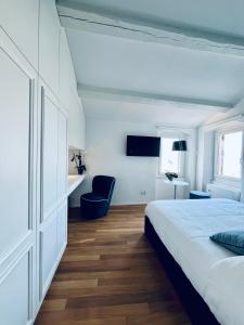 een witte slaapkamer met een bed en een blauwe stoel bij About Italy Holiday Rooms and Apartments in Portovenere