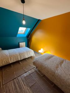 - une chambre avec 2 lits et un mur bleu et jaune dans l'établissement GITES au calme, à Soudan