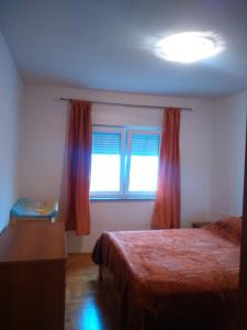 a bedroom with a bed and a window with red curtains at Apartment Hajdo in Rijeka
