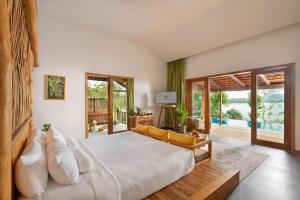 Schlafzimmer mit einem großen weißen Bett und Glasschiebetüren in der Unterkunft Green Bay Phu Quoc Resort & Spa in Phu Quoc