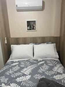 1 cama con 2 almohadas y una foto en la pared en Apartamento Dfplaza luxo, en Brasilia