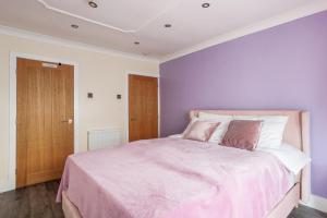 1 dormitorio con paredes moradas y 1 cama con sábanas rosas en SUMMER BREEZE en Horden