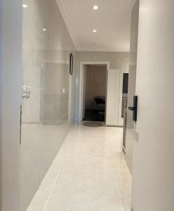 a hallway with a shower and a white tile floor at شقه استديو حي بالمروج in Riyadh
