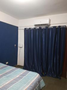 a bedroom with blue curtains and a bed and a heater at Departamento completo en edificio Camilo Recalde 477 in Ciudad del Este
