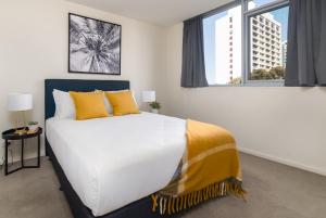 1 dormitorio con 1 cama blanca grande con almohadas amarillas en Central 1-Bed with Parking BBQ and Indoor Pool, en Canberra