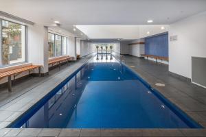 a large pool with blue water in a building at Central 1-Bed with Parking BBQ and Indoor Pool in Canberra