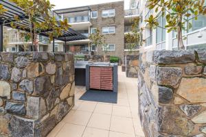 una cocina al aire libre con una pared de piedra en Central 1-Bed with Parking BBQ and Indoor Pool, en Canberra