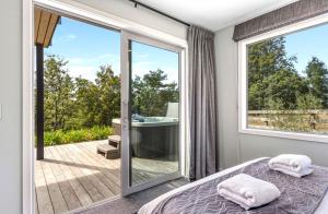 a bedroom with a bed and a large window at Hideaway at the Bay - Taupo. in Taupo