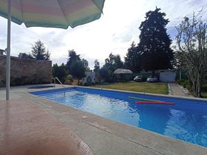 a swimming pool with an umbrella next to a house at Cabañas Elsa María, Cabañas para Hospedaje con Alberca y Jardín de Eventos in Atlautla