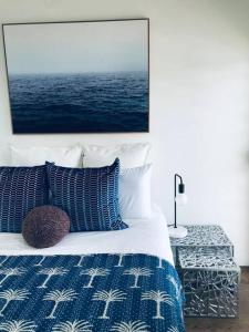 a bedroom with a blue and white bed with a picture on the wall at Harbour View Woolloomooloo in Sydney