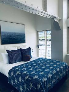 Harbour View Woolloomooloo في سيدني: غرفة نوم بسرير كبير مع بطانية زرقاء وبيضاء